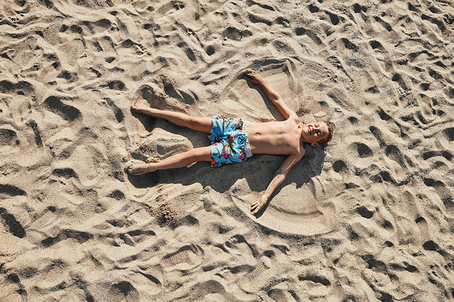 Poika makaa hiekalla