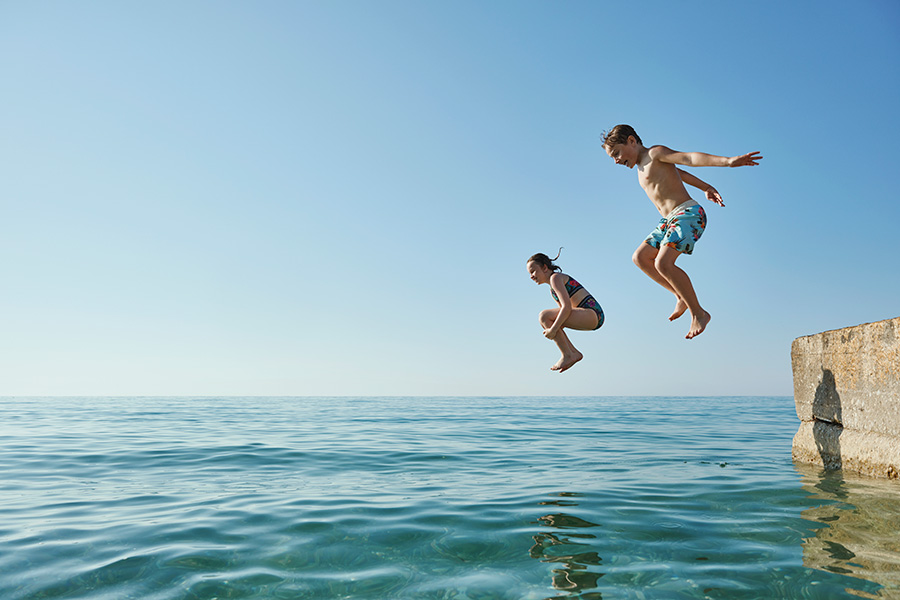 Lapset hyppäävät veteen