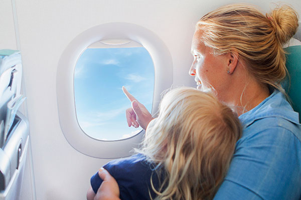 Äiti katsoo lapsen kanssa ulos lentokoneen ikkunasta